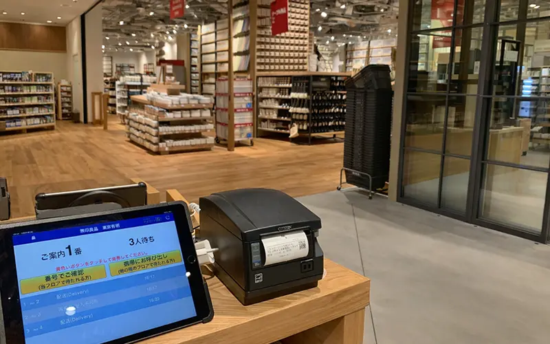 アイリスト設置風景 — 調剤薬局の受付カウンターに設置された端末と調剤完了モニター