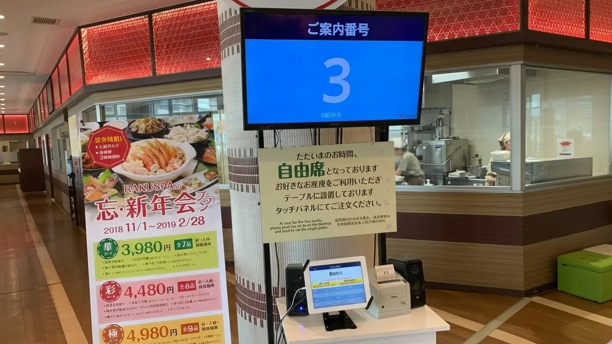 温浴施設のお食事処に設置されたアイリスト — 大型モニターと発券機で順番待ちを管理