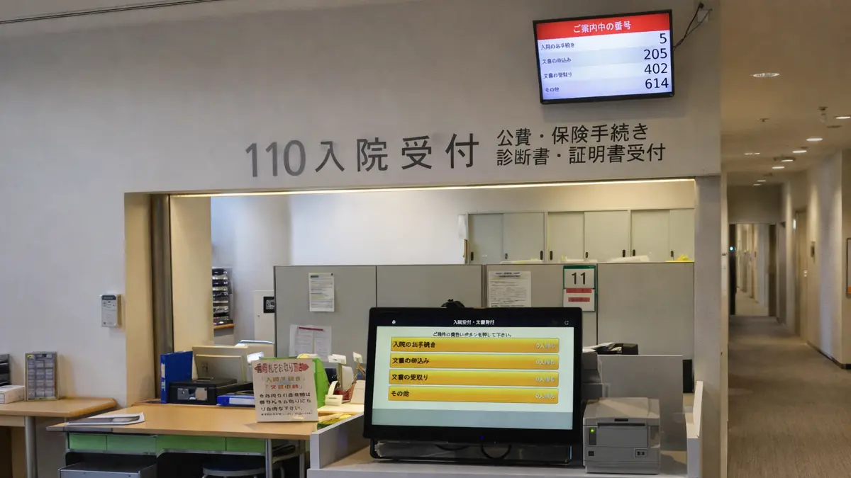 クリニックの受付と待合室イメージ — 番号表示モニターのある清潔な待合空間